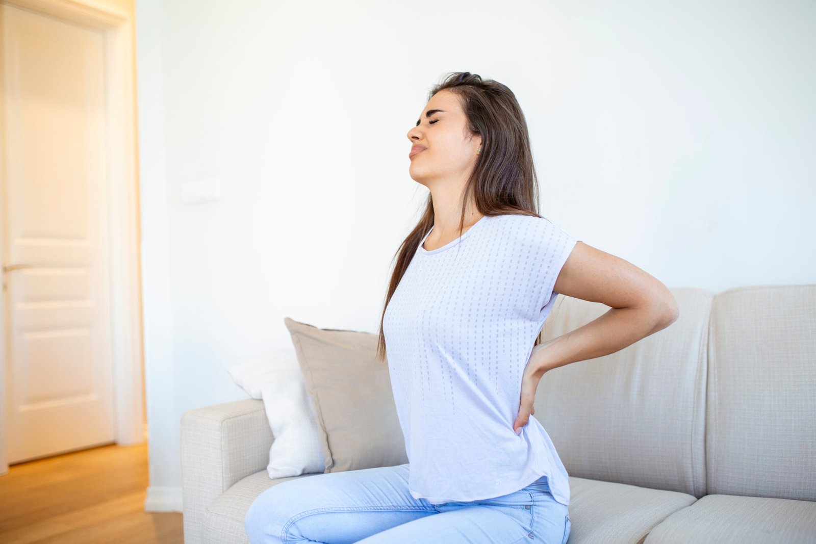 woman suffering from backache home lower back pain woman feels back pain massaging aching muscles sad woman suffers from lowback scaled