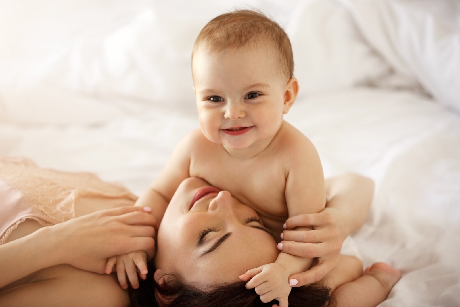 young happy mother her baby daughter smiling embracing lying bed home scaled
